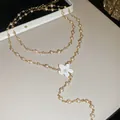 Detalle de un collar de cadena de metal dorado con perlas y un colgante de flor blanca - Collar / Oro-Blanco