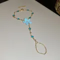 Vista detallada de una pulsera de mano dorada con flor de esmalte azul claro y cristales. - Cadena de mano / Dorado-Azul