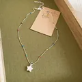 Detail of colorful beaded necklace with a white star-shaped pendant on green background. - Necklace - Silver - Multicolor
