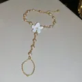 Detalle de una pulsera de dedo de cadena dorada con flor de esmalte blanco y perlas - Cadena de mano / Oro-Blanco