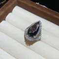 Close-up of a luxurious teardrop purple gemstone ring with sparkling pavé stones. - Open Ring / Purple
