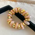 Close-up of a chunky elastic bracelet with marbled peach resin and gold geometric beads - Peach Marble Pattern Beaded Style (63#手链) / Gold-Pink