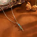 Close-up detail of silver tulip pendant necklace with blue and green gemstones on brown background - Tulip (T079) / Blue Zirconia Necklace / Silver