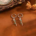 Gros plan d'élégantes boucles d'oreilles tulipes en acier inox avec pierres vertes et claires - Tulipe (T079) / Boucles d'oreilles zircon blanc / Argent
