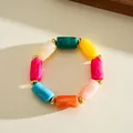 Macro view of a colorful marbled acrylic cylindrical bead bracelet with gold spacers - Bracelet / Gold Multicolor