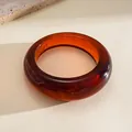 Detailed macro view of a vintage amber marbled resin round bangle featuring a glossy finish - Brown