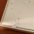 Vue détaillée d'un collier fleur en verre dopamine coloré avec une chaîne à billes argentée - Rose