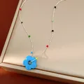 Vue détaillée d'un collier coloré style dopamine avec pendentif fleur en verre bleu - Bleu