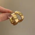 Close-up of gold-colored chunky hoop earrings with black polka dot pattern details. - Frosted Brushed Polka Dot Hoop Style (59#) / Gold