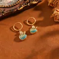 Orecchini a cerchio a forma di cigno dorato con pietra occhio di gatto blu e zirconi. - Orecchini A Cigno T064 In Oro E Diamanti Blu