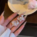 Close-up of elegant flower basket earrings with pearls and white shell petals - Ear Huggies (HE34042) / White