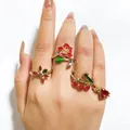 Detalle de cerca del juego de cuatro anillos florales dorados usados en el dedo - Juego de flores y corazones rojos (32955-ring-red)