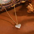 Detail einer goldenen Herzhalskette mit klaren Zirkonia auf einer Vintage-Oberfläche. - Goldene Halskette mit drei weißen Strass-Herzen (T076)