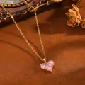 Nahaufnahme eines rosafarbenen Herz-Zirkonia-Anhängers an einer goldenen Edelstahlkette - Goldene Halskette mit drei rosa Strass-Herzen (T076)