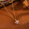 Detailaufnahme einer goldfarbenen Halskette mit elegantem rosa Kristall-Blumenanhänger - Goldene Halskette mit weißem Herz und rosa fünfblättriger Blume (T077)