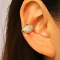 Detailed view of an elegant gold-plated shell ear cuff adorned with sparkling zircons. - Shell (0001) / Gold