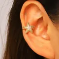 Close-up of a gold-plated starfish ear cuff with sparkling cubic zirconia on a model's ear - Starfish (8849) / Gold