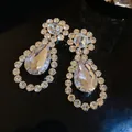 Macro view of luxurious teardrop crystal earrings for bridal dinner party outfits - Gold