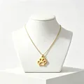 Detailed view of a gold-plated stainless steel paw print pendant necklace on a display bust. - Gold