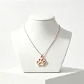 Detailed view of a rose gold paw print pendant necklace on a white jewelry display stand. - Rose Gold
