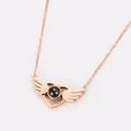 Macro detail of rose gold heart pendant with angel wings and projection stone inlay. - Rose Gold