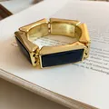 Dettaglio ravvicinato di un bracciale elastico a segmenti rettangolari in resina oro e blu - Blu