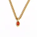 Primo piano di una collana in acciaio inossidabile dorato con pendente in zircone rosso marquise. - Rosso