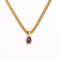 Macro dettagliata di un ciondolo in zircone viola su una catena a maglia dorata. - Viola