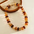 Close-up of vintage multi-colored marbled acrylic bead necklace with gold-toned clasp - Necklace / Amber