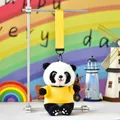 Close-up of a cute panda plush keychain with yellow t-shirt hanging on metal display stand - Yellow