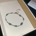 Detailopname van een verzilverde armband met groene gefacetteerde kralen in doosje. - Armband / Zilver-Groen