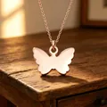 Detailopname van een vlinderhanger ketting in roségoud met een gladde spiegelafwerking - Vlinder Hanger Ketting (Roségoud)