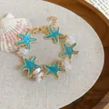 Detail view of a blue enamel starfish and pearl bracelet presented on a rustic fabric backdrop. - Blue-Green Starfish Ocean Style (68#手链) / Gold-Blue