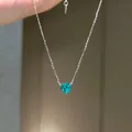 Nahaufnahme einer silbernen Halskette mit einem funkelnden blaugrünen Herz-Zirkon - Halskette / Grün