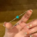 Detailansicht eines eleganten Silberarmbands mit blauem, herzförmigem Zirkonstein - Armband / Grün