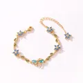 Vue détaillée d'un élégant bracelet doré avec fleurs en zircon bleu et nœud papillon. - Style Horizontal-Or-Zirconia Bleu Mer