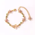 Gros plan détaillé d'un bracelet doré orné de fleurs roses, d'un nœud et de feuilles - Style Horizontal-Or-Zirconia Rose