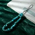 Macro view of a natural turquoise chip stone phone lanyard strap on green velvet - Blue Green (Turquoise)