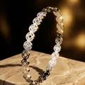 Detalle de brazalete de acero inoxidable plateado con patrón calado sobre base mármol - Brazalete de Moneda Color Acero (39-E-4)