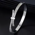 Primo piano di un bracciale in acciaio inossidabile argento con cristalli quadrati e fiocco - Argento Strass Bianco