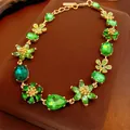 Vintage style gold necklace with vibrant green crystal floral motifs on display - Flower Necklace / Gold-Green
