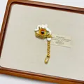 Macro view of vintage gold-tone evil eye ring with white enamel drip and dangling chain - Colorful Evil Eye Brooch Xz0163a