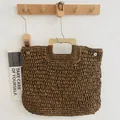 Handgefertigte gewebte Strohhandtasche mit quadratischem Holzgriff an Wandregal - Dunkelbraun