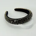 Primo piano di cerchietto barocco imbottito con strass neri e ganci dorati fini - Nero