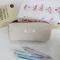 Detail of minimalist beige stationery storage bag with red zipper and brand tag - 19x6x7cm / Khaki
