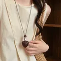 Vista dettagliata di una collana vintage con pendente a cuore in legno su abiti di lino - Collana con perline a cuore in legno con venature verticali - circa 97 cm
