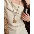 Collana lunga minimalista con un disco di legno intagliato su un vestito di lino - Collana a disco beige a rete - circonferenza circa 88 cm