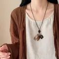 Collana lunga stile cinese moderno con ciondoli misti indossata da una modella - Collana tonda vuota con fiori e foglie - circonferenza circa 84 cm