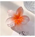 Macro view of translucent gradient plumeria flower hair claw clip for vacation style - 8cm Orange