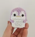 Primo piano di un pinguino viola fatto a mano all'uncinetto con messaggio positivo - Pinguino / Viola